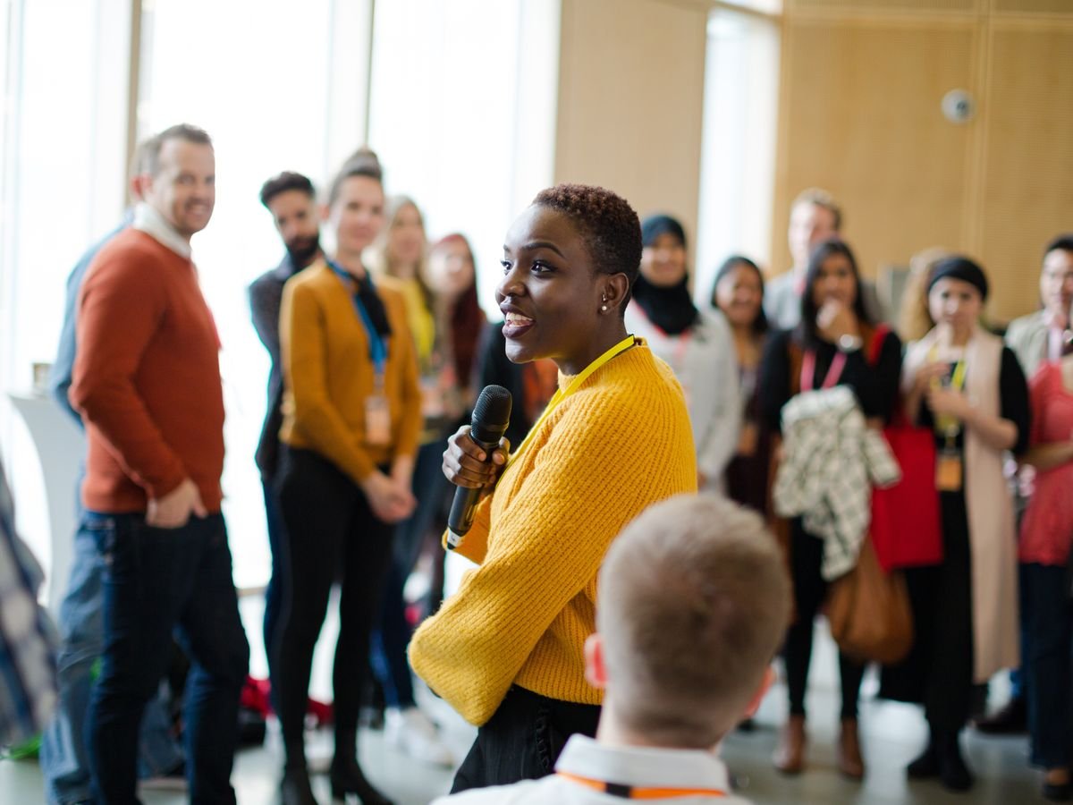 A woman speaking to a room with a microphone