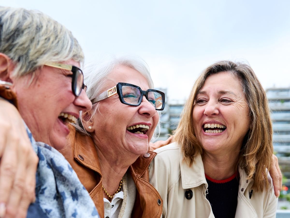 Three women laughing together outdoors